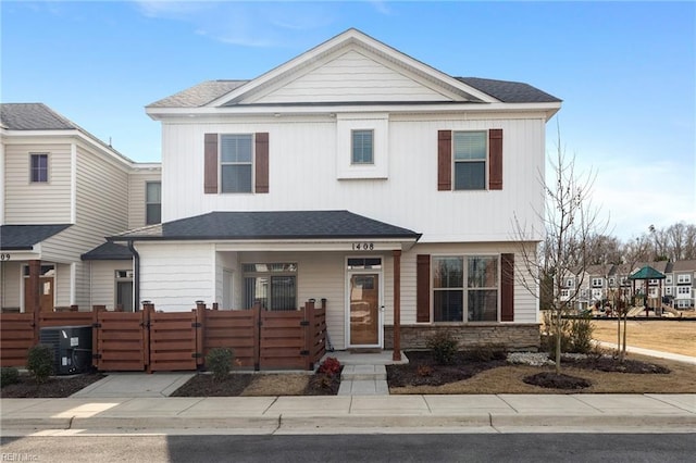 view of front of home featuring central AC unit, a fenced front yard, stone siding, roof with shingles, and a gate