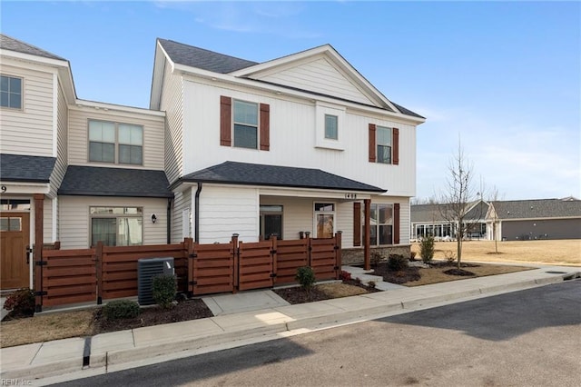 multi unit property featuring a fenced front yard, a gate, cooling unit, and roof with shingles