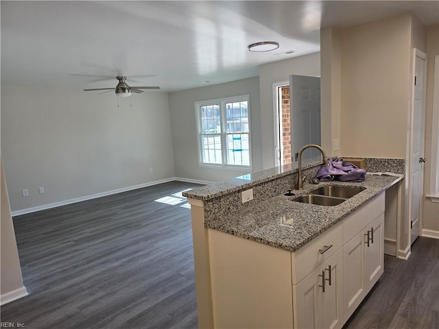 kitchen featuring visible vents, baseboards, dark wood-type flooring, light stone countertops, and a sink