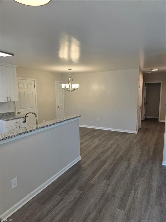 interior space featuring a sink, an inviting chandelier, baseboards, and dark wood-type flooring