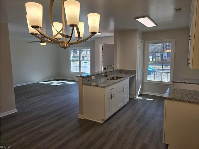 kitchen featuring dark wood-type flooring, white cabinetry, a sink, and light stone counters