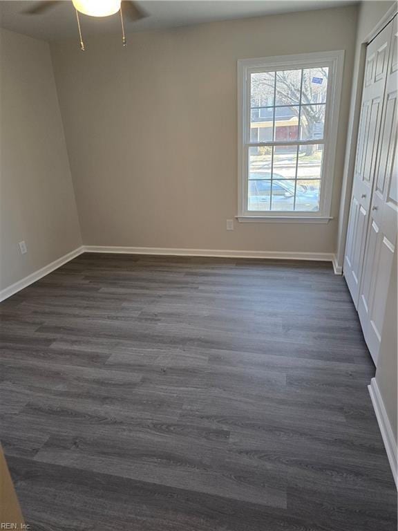 unfurnished room with ceiling fan, dark wood-type flooring, and baseboards