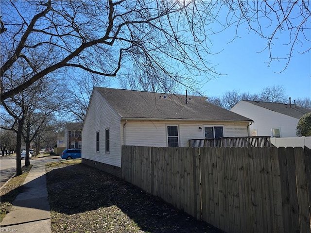 view of property exterior featuring roof with shingles and fence