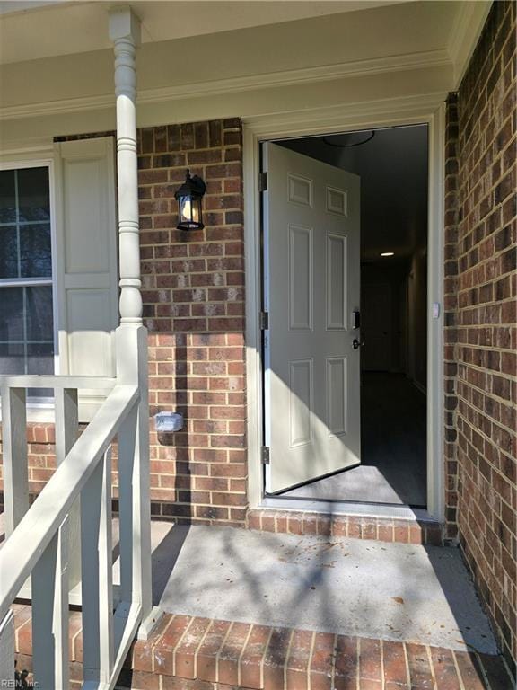 entrance to property featuring brick siding and a porch