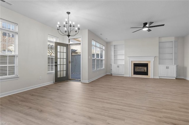 unfurnished living room featuring light wood finished floors, baseboards, visible vents, built in features, and a fireplace