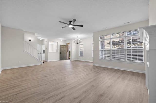 unfurnished living room with light wood finished floors, visible vents, stairway, baseboards, and ceiling fan with notable chandelier