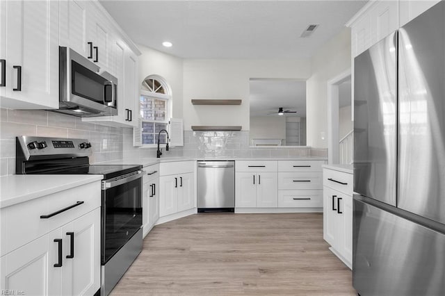 kitchen with light wood finished floors, tasteful backsplash, appliances with stainless steel finishes, light countertops, and open shelves