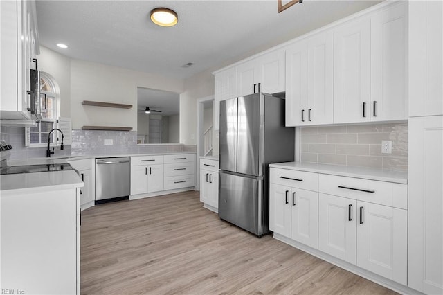 kitchen featuring light wood-style flooring, white cabinets, light countertops, appliances with stainless steel finishes, and open shelves