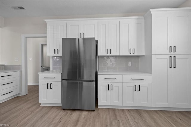 kitchen featuring visible vents, light countertops, light wood-style flooring, and freestanding refrigerator