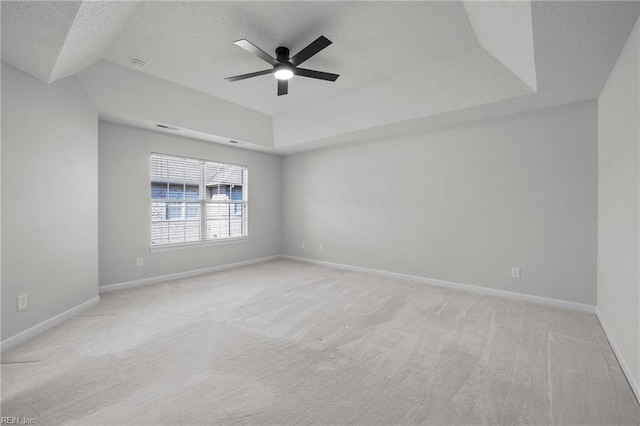 spare room featuring baseboards, a raised ceiling, a ceiling fan, and light colored carpet