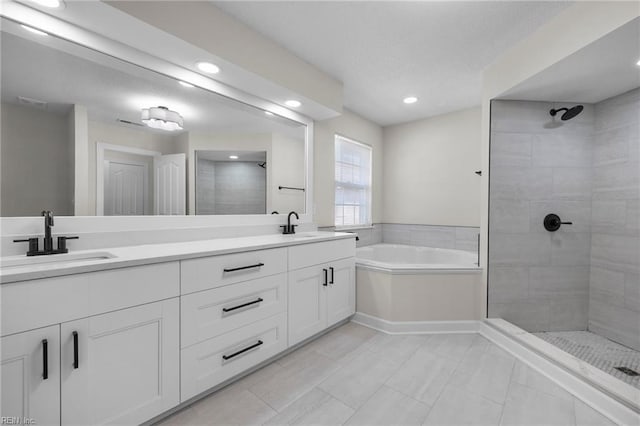 bathroom with tiled shower, a sink, a bath, and double vanity