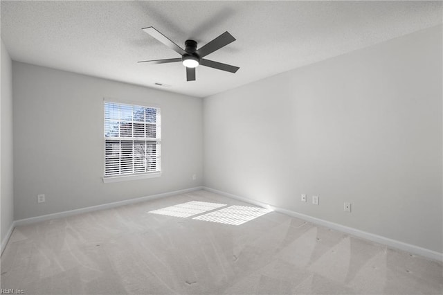 carpeted empty room with ceiling fan, a textured ceiling, and baseboards