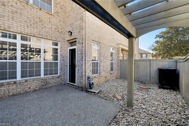 exterior space featuring brick siding, fence, and a patio