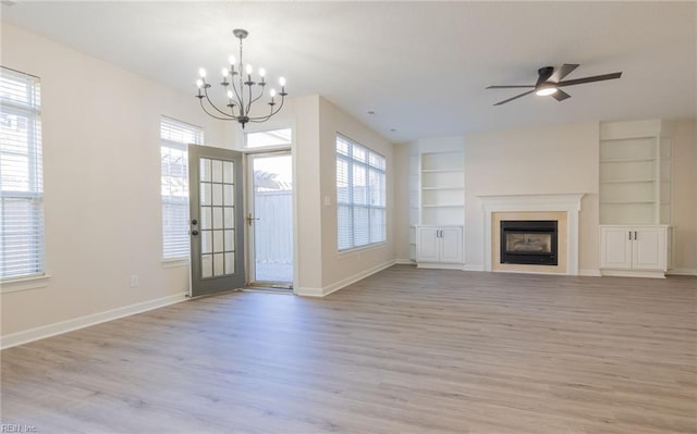 unfurnished living room featuring baseboards, a fireplace, built in features, and a wealth of natural light