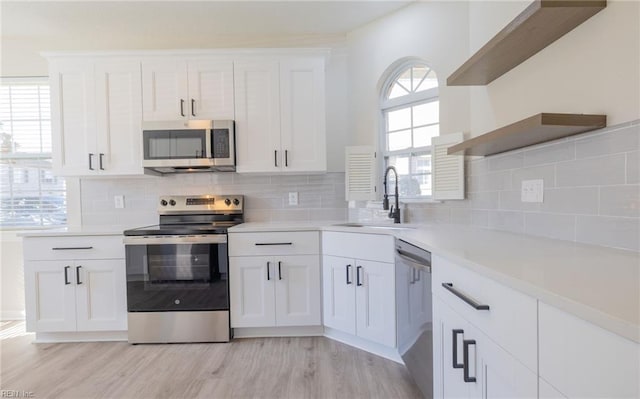 kitchen featuring stainless steel appliances, white cabinets, a sink, and open shelves