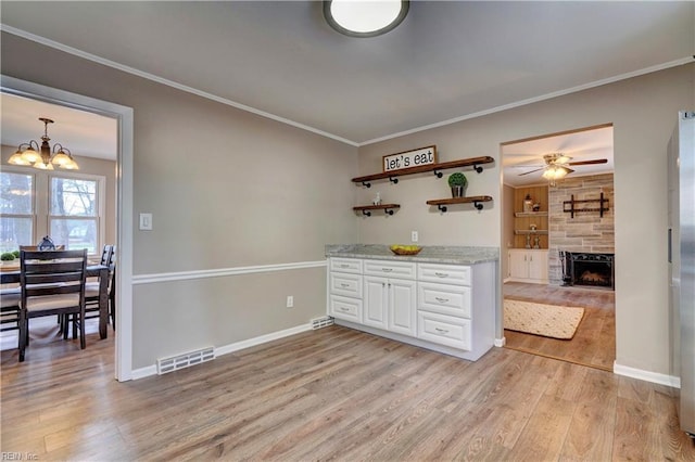 kitchen with light wood-style floors, visible vents, and crown molding