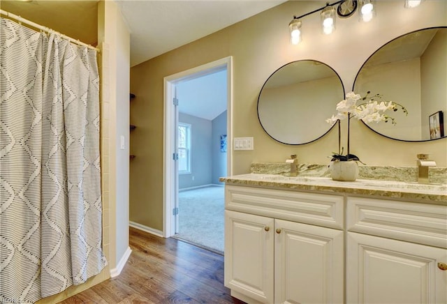 bathroom with lofted ceiling, wood finished floors, vanity, baseboards, and a shower with curtain