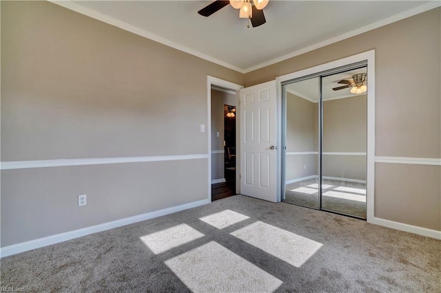 unfurnished bedroom with ceiling fan, carpet flooring, baseboards, ornamental molding, and a closet