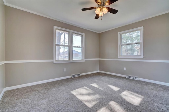 carpeted empty room with visible vents, crown molding, and baseboards