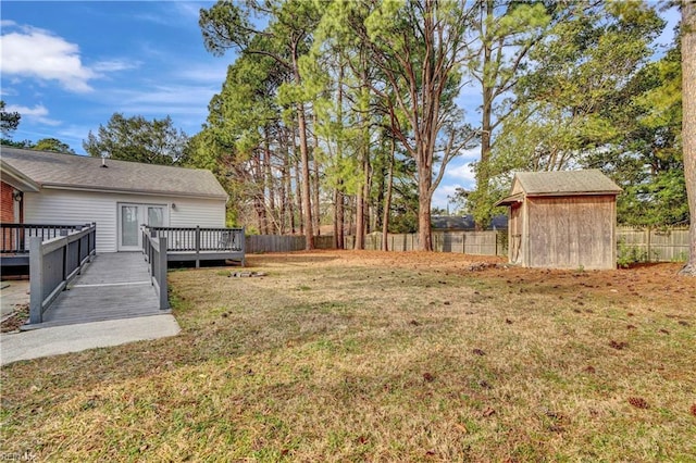 view of yard featuring a fenced backyard, a storage unit, a deck, and an outbuilding