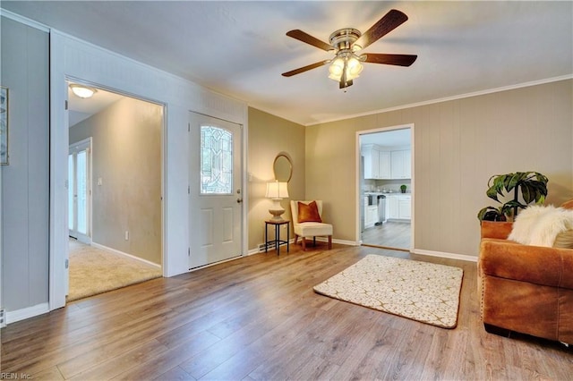 entrance foyer with ornamental molding, a ceiling fan, baseboards, and wood finished floors