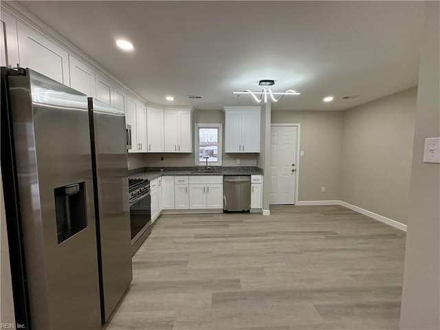 kitchen with light wood finished floors, white cabinets, stainless steel appliances, and a sink