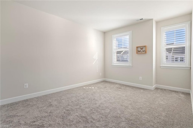 empty room with visible vents, light carpet, and baseboards