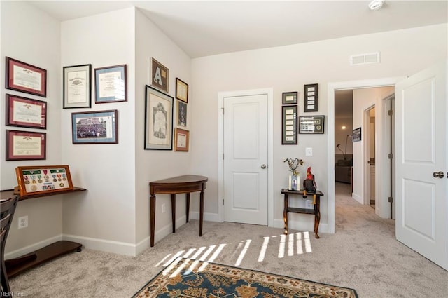 hall featuring baseboards, visible vents, and carpet flooring