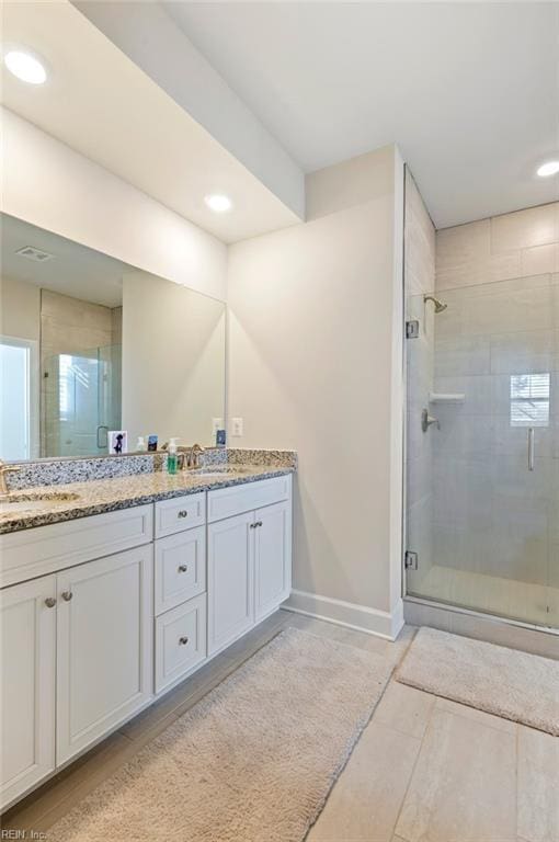 full bath featuring double vanity, a stall shower, and a sink