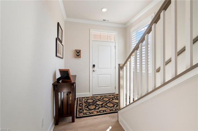 entrance foyer with visible vents, crown molding, baseboards, and wood finished floors