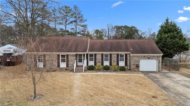 view of front of property featuring brick siding, concrete driveway, an attached garage, fence, and a front yard