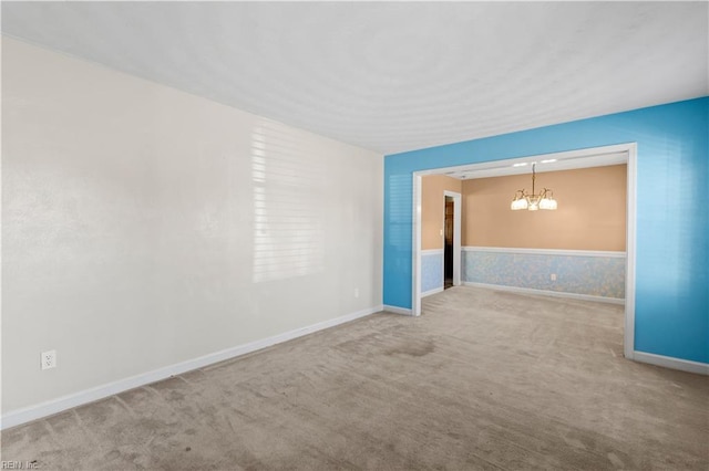 carpeted empty room with a chandelier and baseboards