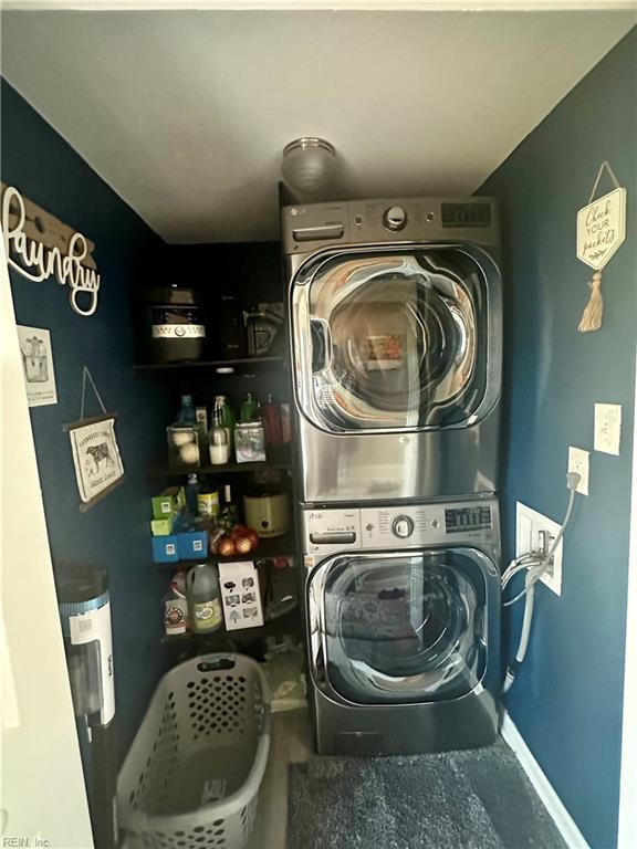 washroom with stacked washer and dryer, laundry area, and baseboards