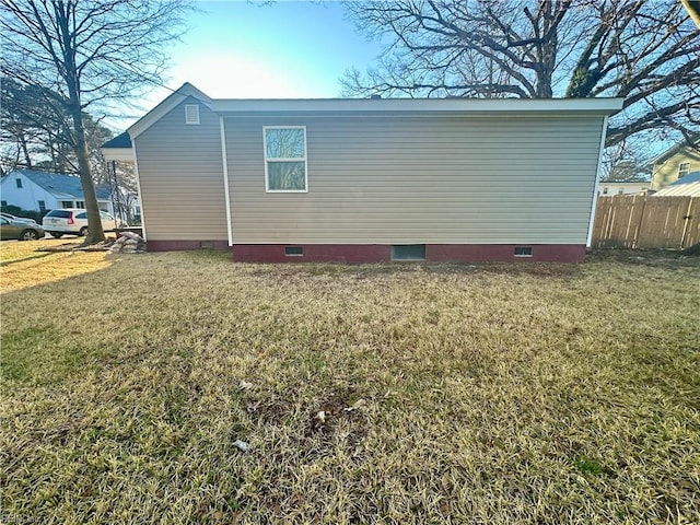 view of property exterior with crawl space, a yard, and fence