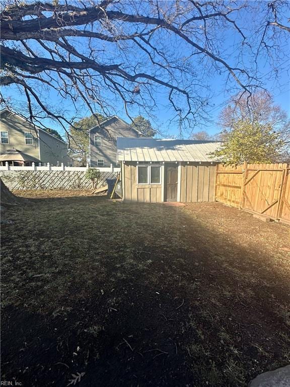 view of yard with a fenced backyard, a storage unit, and an outbuilding