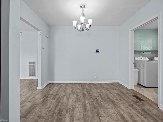 unfurnished dining area featuring wood finished floors, washing machine and dryer, and visible vents