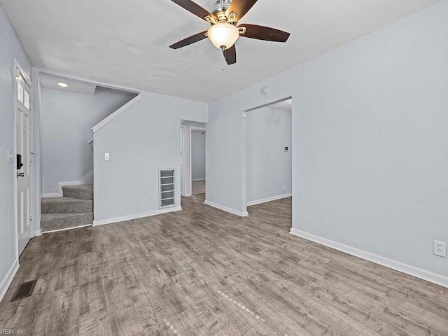 unfurnished living room with baseboards, stairs, visible vents, and wood finished floors