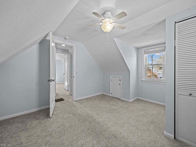 additional living space featuring carpet floors, a ceiling fan, vaulted ceiling, a textured ceiling, and baseboards