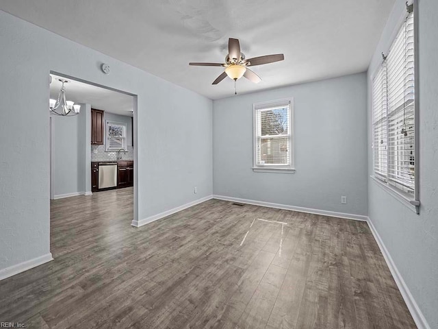 unfurnished room with dark wood-style flooring, a sink, a wealth of natural light, and baseboards