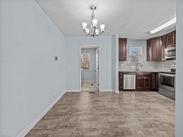 kitchen with stainless steel appliances, tasteful backsplash, light wood-style flooring, and a wealth of natural light