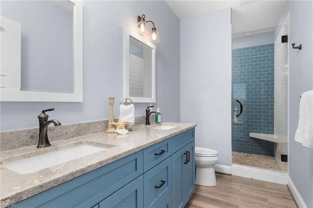 full bathroom featuring wood finished floors, a stall shower, a sink, and toilet