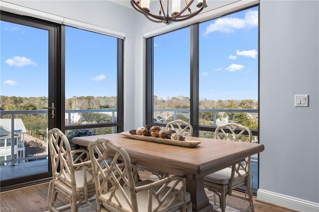 dining room with a notable chandelier, baseboards, and wood finished floors