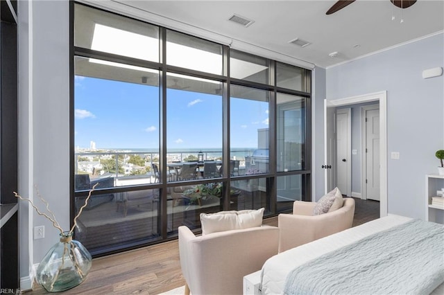 bedroom with crown molding, wood finished floors, visible vents, and floor to ceiling windows