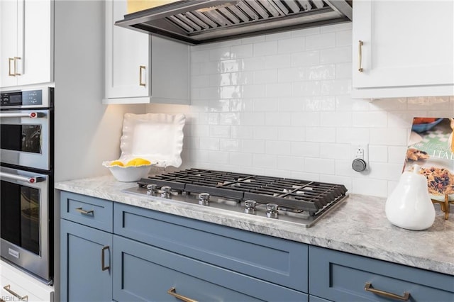 kitchen featuring blue cabinets, appliances with stainless steel finishes, white cabinetry, and custom range hood