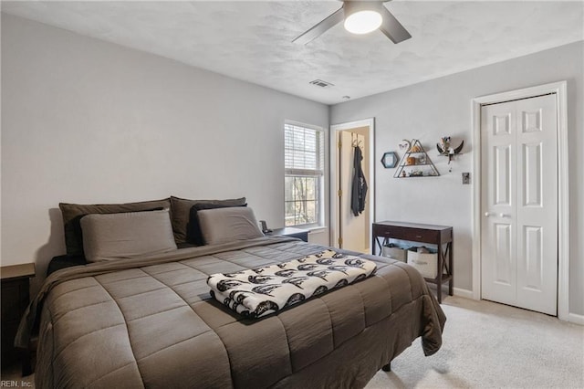 bedroom featuring light colored carpet, a ceiling fan, baseboards, visible vents, and a closet