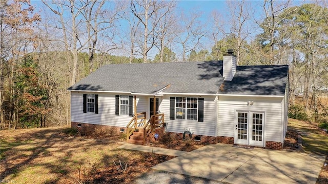 view of front of property featuring crawl space, a shingled roof, a chimney, and french doors