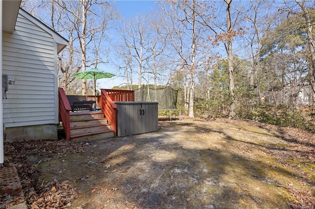 view of yard with a trampoline and a wooden deck