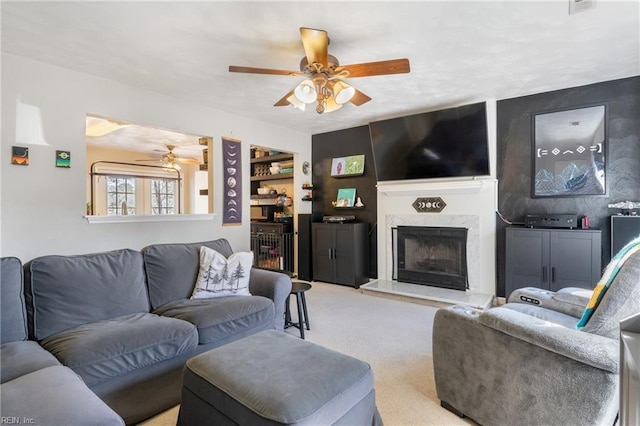 living area with ceiling fan, carpet, built in shelves, and a fireplace