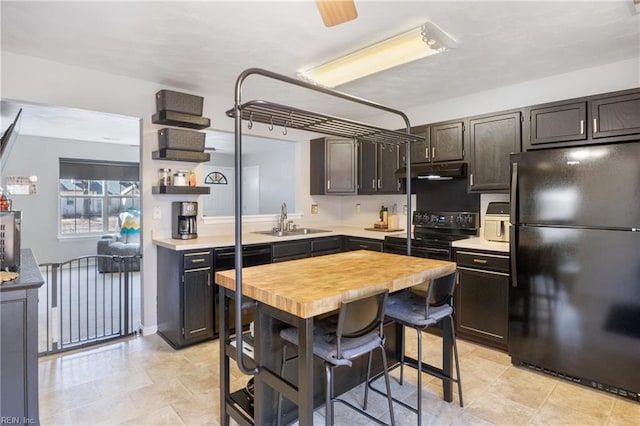 kitchen featuring black appliances, under cabinet range hood, light countertops, and a sink