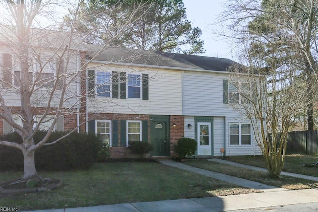 view of front of property with a front yard, brick siding, and fence